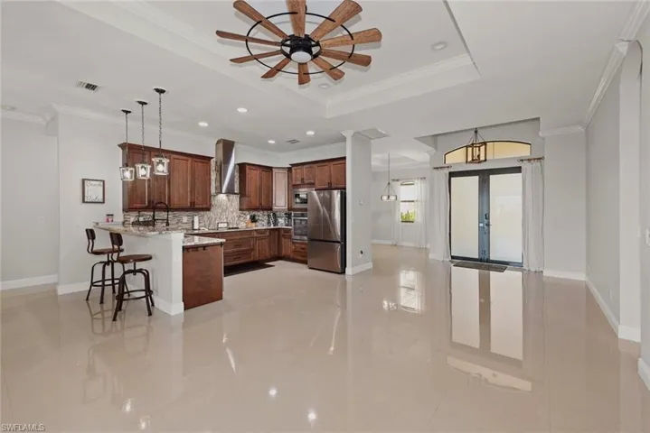 Kitchen featuring a kitchen breakfast bar, a peninsula, decorative light fixtures, ornamental molding, and french doors