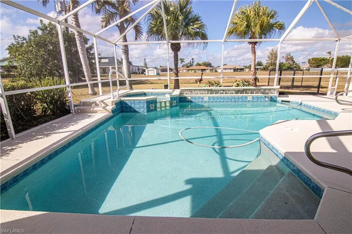 View of swimming pool featuring glass enclosure and a patio