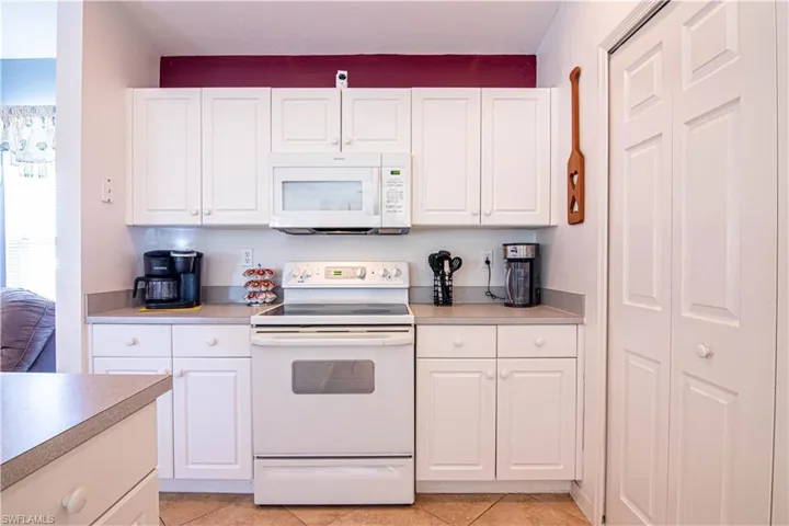 Kitchen with white cabinets, white appliances, and light tile patterned floors