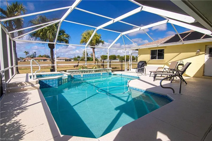 View of swimming pool with glass enclosure, an in ground hot tub, and a patio