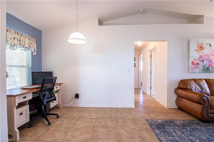Home office with light tile patterned floors and lofted ceiling