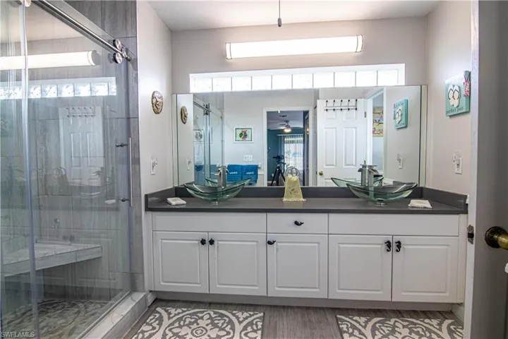 Bathroom featuring hardwood / wood-style floors, vanity, a shower with door, and ceiling fan