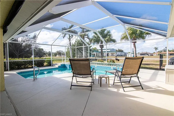View of pool with glass enclosure and a patio area