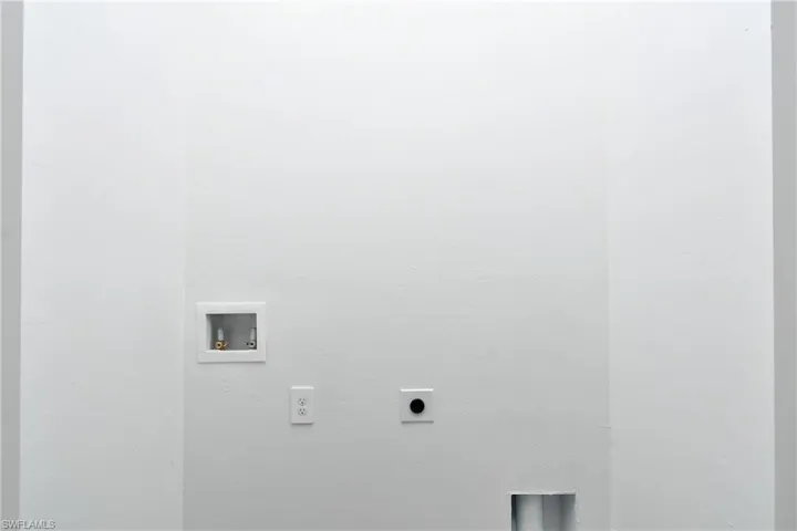 White wall finish, laundry hookup box, electrical outlet, dryer vent hookup