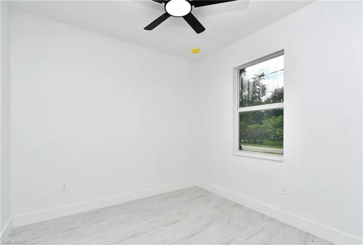 White walls, tile flooring, and a ceiling fan with integrated lighting