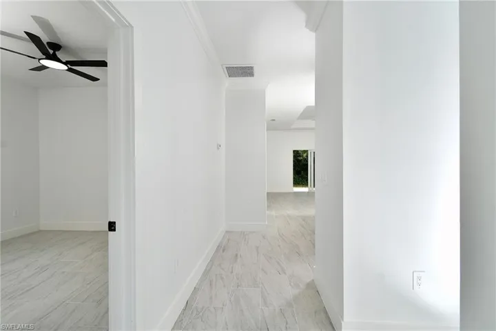 White tile flooring throughout, white baseboards, and crown molding