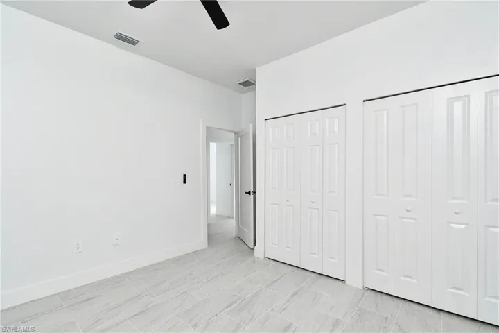 White panel bi-fold doors, tile flooring, recessed ceiling, modern ceiling fan, and white baseboards
