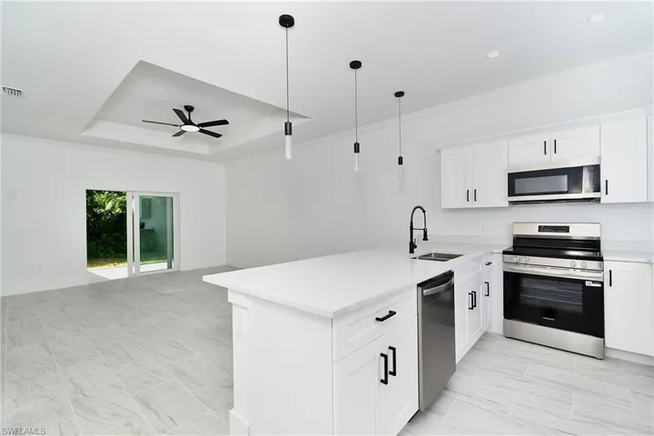 White shaker cabinetry, stainless steel appliances, and a kitchen island with pendant lighting
