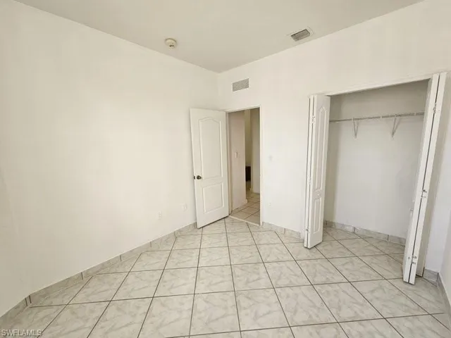 Unfurnished bedroom featuring light tile patterned flooring and a closet