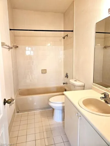 Full bathroom with tiled shower / bath combo, vanity, tile patterned flooring, and toilet