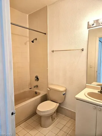 Full bathroom with tiled shower / bath combo, vanity, tile patterned flooring, and toilet