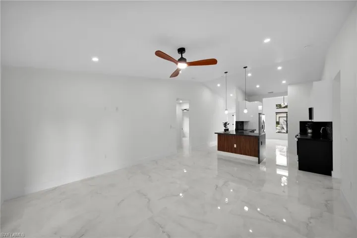 Unfurnished living room featuring a ceiling fan, baseboards, marble finish floor, lofted ceiling, and recessed lighting