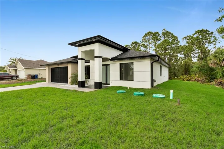 View of front of home featuring a front yard, concrete driveway, an attached garage, a shingled roof, and stucco siding