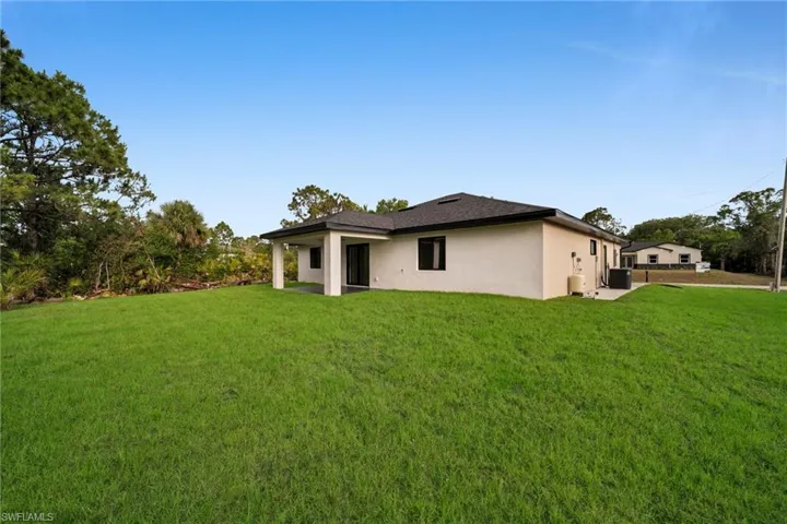 Back of property featuring stucco siding and a yard