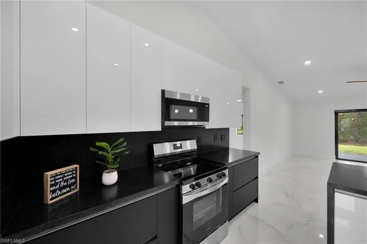 Kitchen featuring marble finish floor, dark countertops, modern cabinets, white cabinetry, and stainless steel appliances