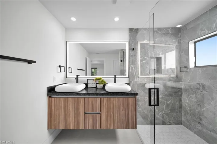 Bathroom with double vanity, recessed lighting, a shower stall, and a sink