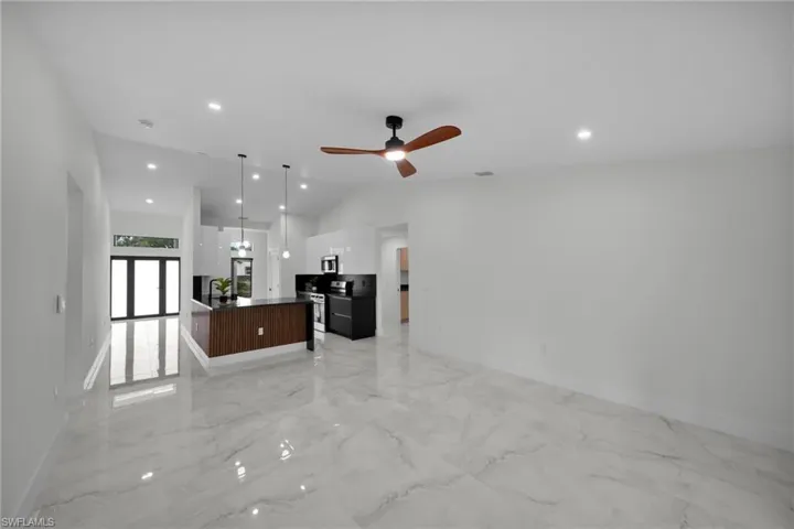 Unfurnished living room featuring baseboards, a ceiling fan, lofted ceiling, and recessed lighting