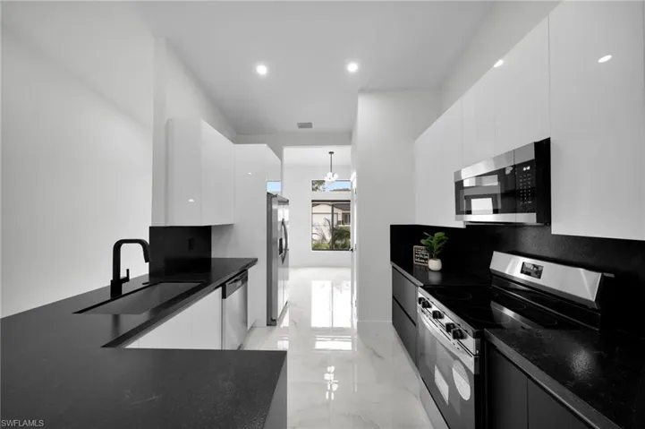 Kitchen featuring stainless steel appliances, a sink, marble finish floor, and modern cabinets
