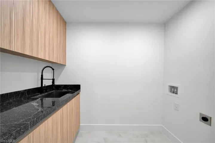 Laundry area with cabinet space, washer hookup, a sink, baseboards, and hookup for an electric dryer