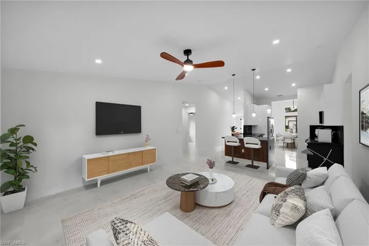 Living area with a ceiling fan, vaulted ceiling, recessed lighting, and marble finish floor