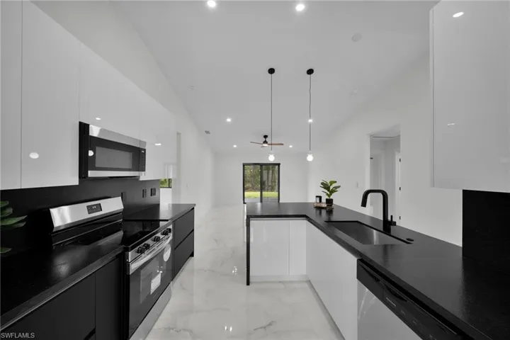 Kitchen featuring marble finish floor, modern cabinets, white cabinets, a sink, and stainless steel appliances