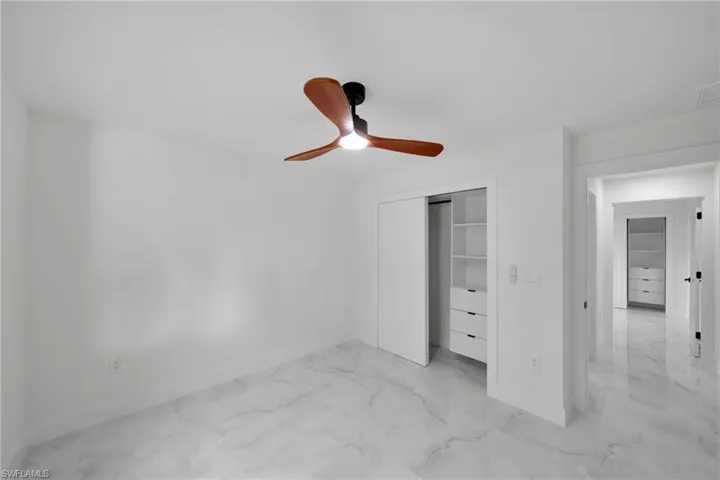 Unfurnished bedroom with baseboards, marble finish floor, and a closet