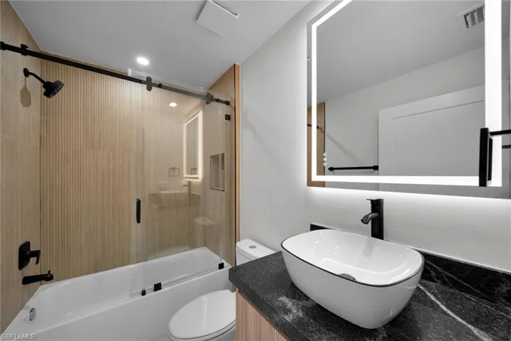 Bathroom featuring vanity, toilet, recessed lighting, combined bath / shower with glass door, and visible vents