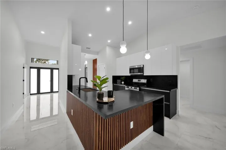 Kitchen featuring dark countertops, appliances with stainless steel finishes, modern cabinets, and marble finish floor