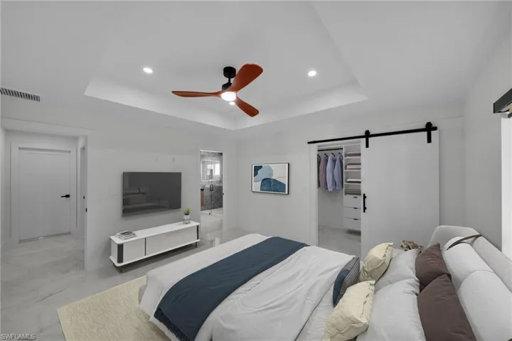 Bedroom with visible vents, a barn door, a tray ceiling, and recessed lighting