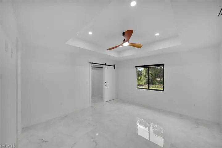 Spare room featuring baseboards, recessed lighting, marble finish floor, and a tray ceiling