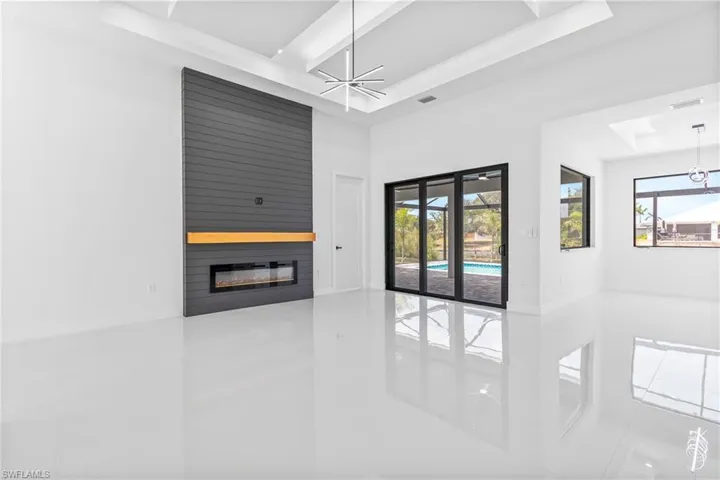 Unfurnished living room featuring a tray ceiling, tile patterned floors, a fireplace, and healthy amount of natural light