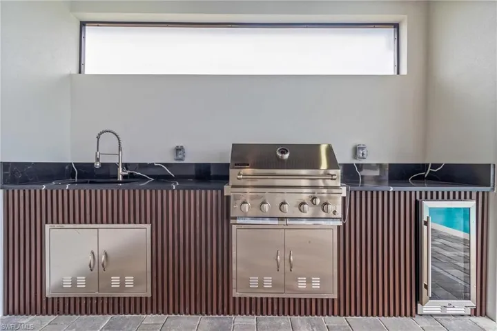 View of patio with wine cooler and a grill