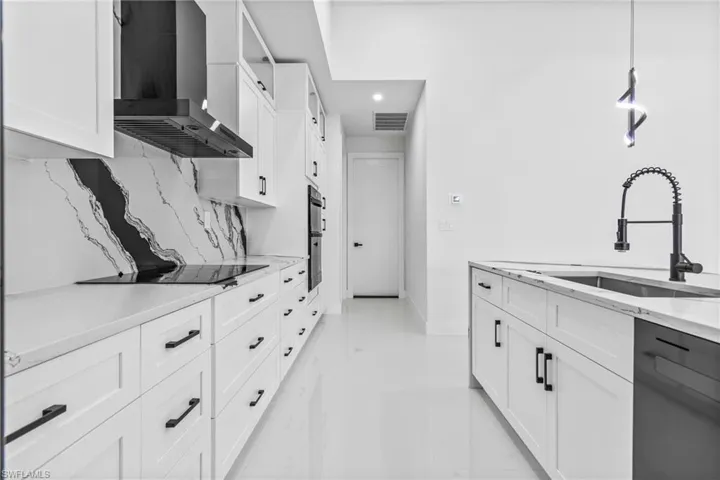 Kitchen with wall chimney range hood, black electric stovetop, dishwasher, white cabinetry, and recessed lighting