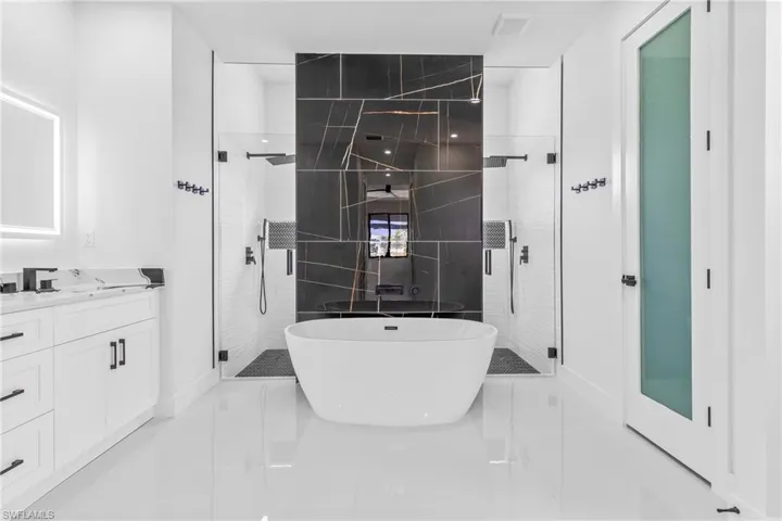 Full bathroom with a stall shower, vanity, a freestanding tub, and tile patterned flooring