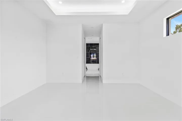 Unfurnished room featuring a tray ceiling, tile patterned flooring, and recessed lighting
