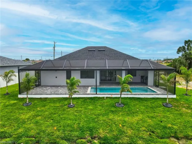 Rear view of house with a patio, a lawn, an outdoor pool, and glass enclosure