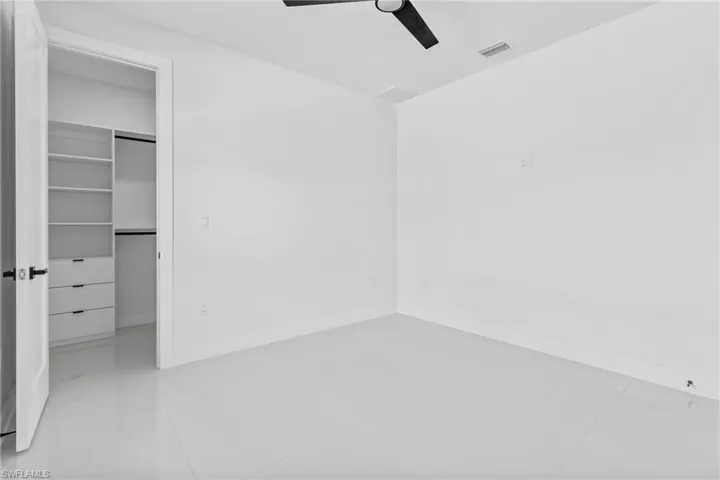 Unfurnished bedroom with a spacious closet, ceiling fan, a closet, and light tile patterned floors