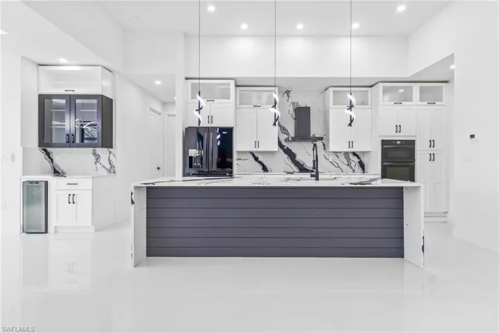 Kitchen with black appliances, wine cooler, recessed lighting, tasteful backsplash, and a large island