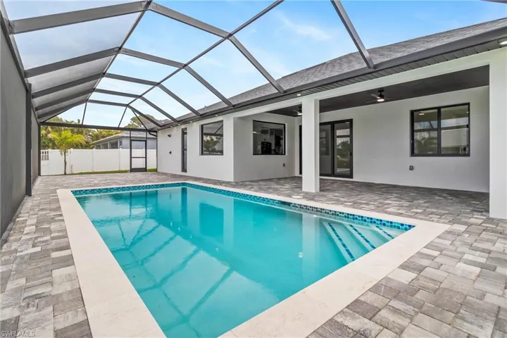 View of pool featuring a patio area, glass enclosure, and a ceiling fan