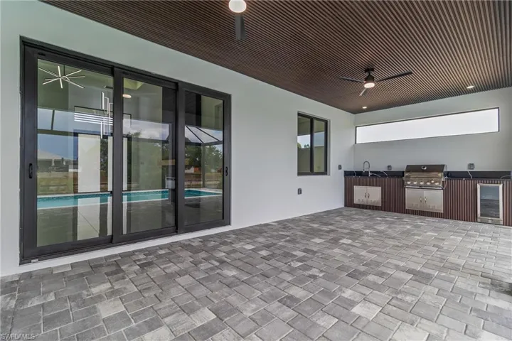 View of patio featuring an outdoor kitchen, a ceiling fan, and wine cooler