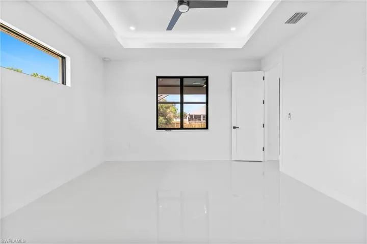 Unfurnished room with plenty of natural light, a raised ceiling, a ceiling fan, and recessed lighting