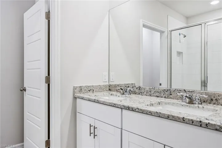 Full bath with double vanity, a stall shower, and recessed lighting