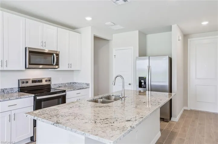 Kitchen featuring stainless steel appliances, a sink, baseboards, white cabinets, and recessed lighting