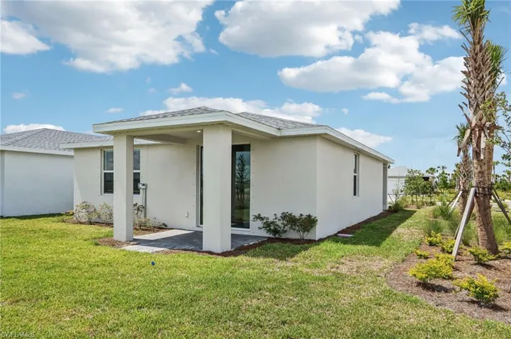 Back of house featuring stucco siding, a lawn, and a patio area