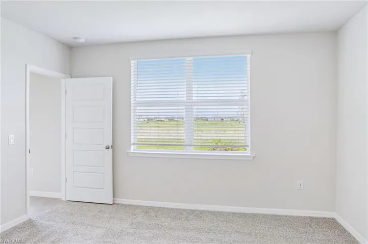 Unfurnished room featuring light carpet, baseboards, and a smoke detector
