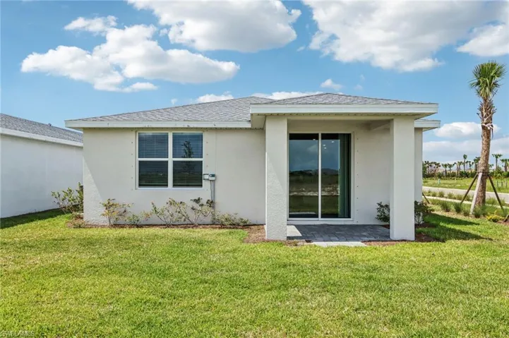 Rear view of property featuring stucco siding, a lawn, and a patio area