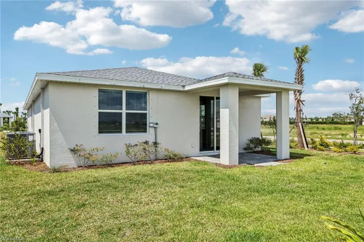 Back of house featuring stucco siding, central air condition unit, a patio area, and a lawn