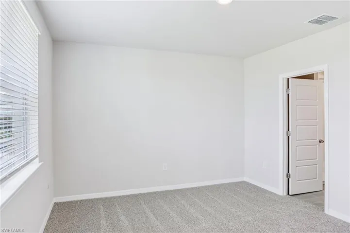 Empty room featuring light colored carpet and baseboards