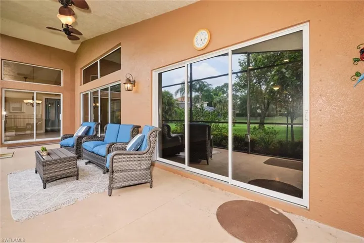 Covered outdoor patio with a ceiling fan, vaulted ceiling, exterior wall lantern, and multiple sliding glass doors