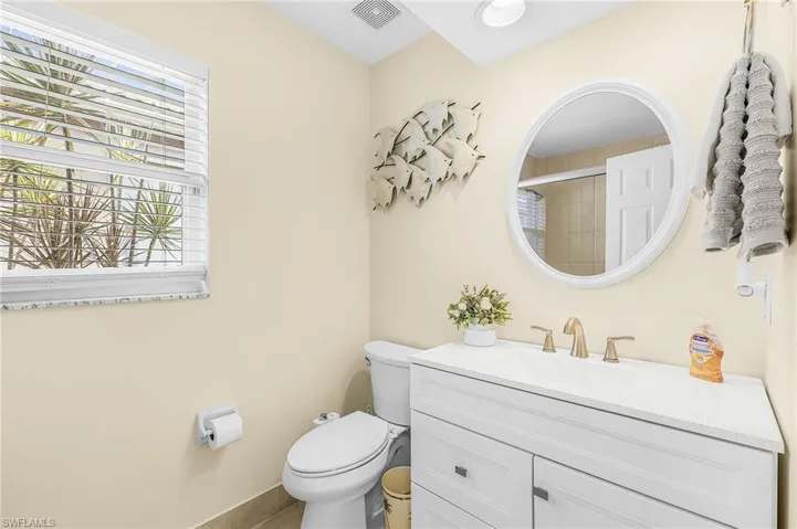 White vanity with a white countertop and brass-finish faucet